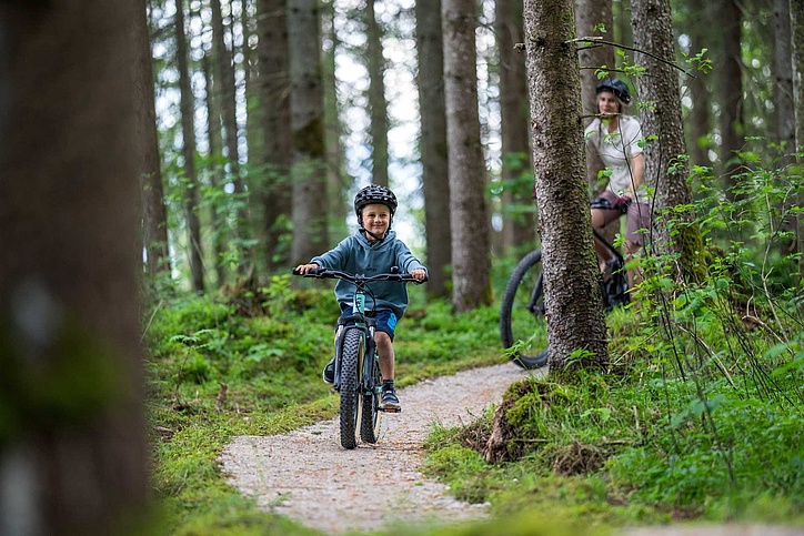 Kind das auf Kiesweg im Wald fährt
