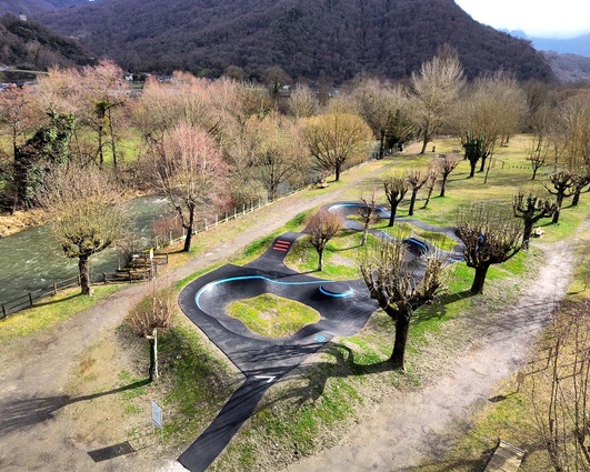 Elevated view of the nature-integrated pumptrack facility next to a river in Saint-Béat-Lez.