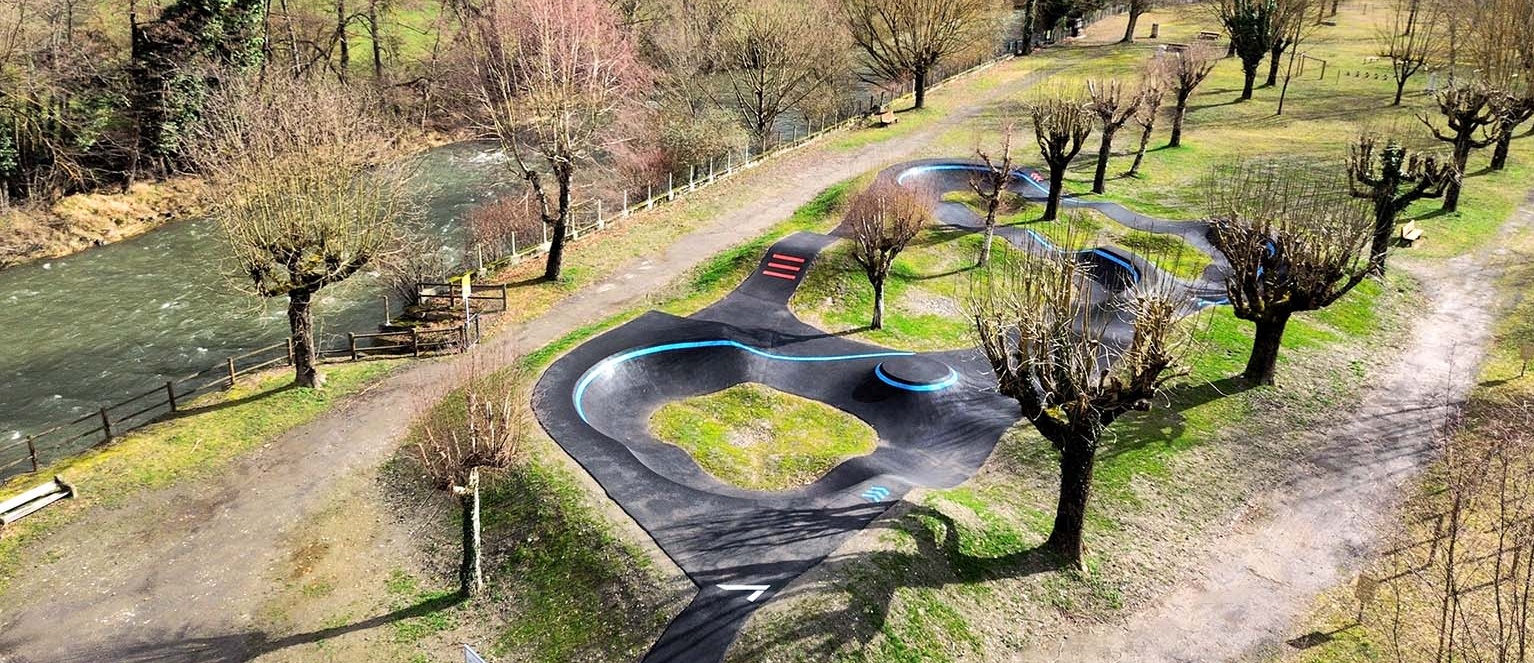 Erhöhte Ansicht der in die Natur integrierten Pumptrack-Anlage neben einem Fluss in Saint-Béat-Lez.