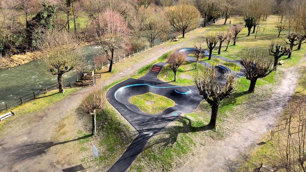Erhöhte Ansicht der in die Natur integrierten Pumptrack-Anlage neben einem Fluss in Saint-Béat-Lez.