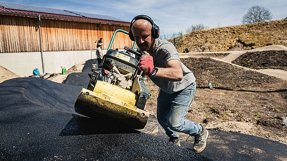 [Translate to Französisch:] Schneestern employee with vibratory plate building a pump track