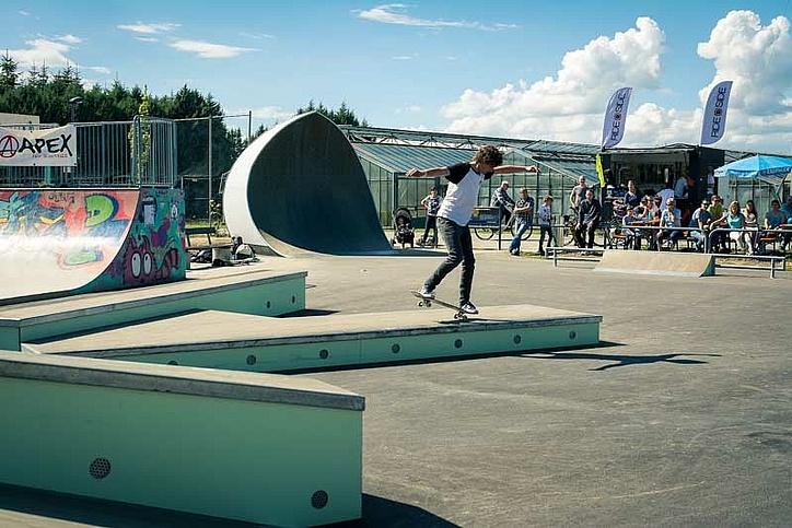 Skateboarder macht Nose Wheelie auf einer Box in einem Skatepark