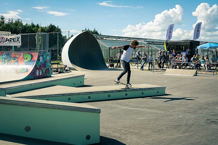 Skateboarder does nose wheelie on a box in a skatepark