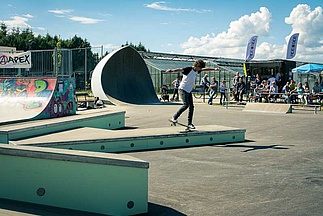 Skateboarder does nose wheelie on a box in a skatepark