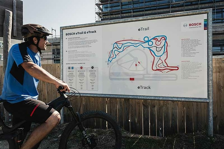 [Translate to Französisch:] Biker steht vor Übersichtstafel vom eBike Trail