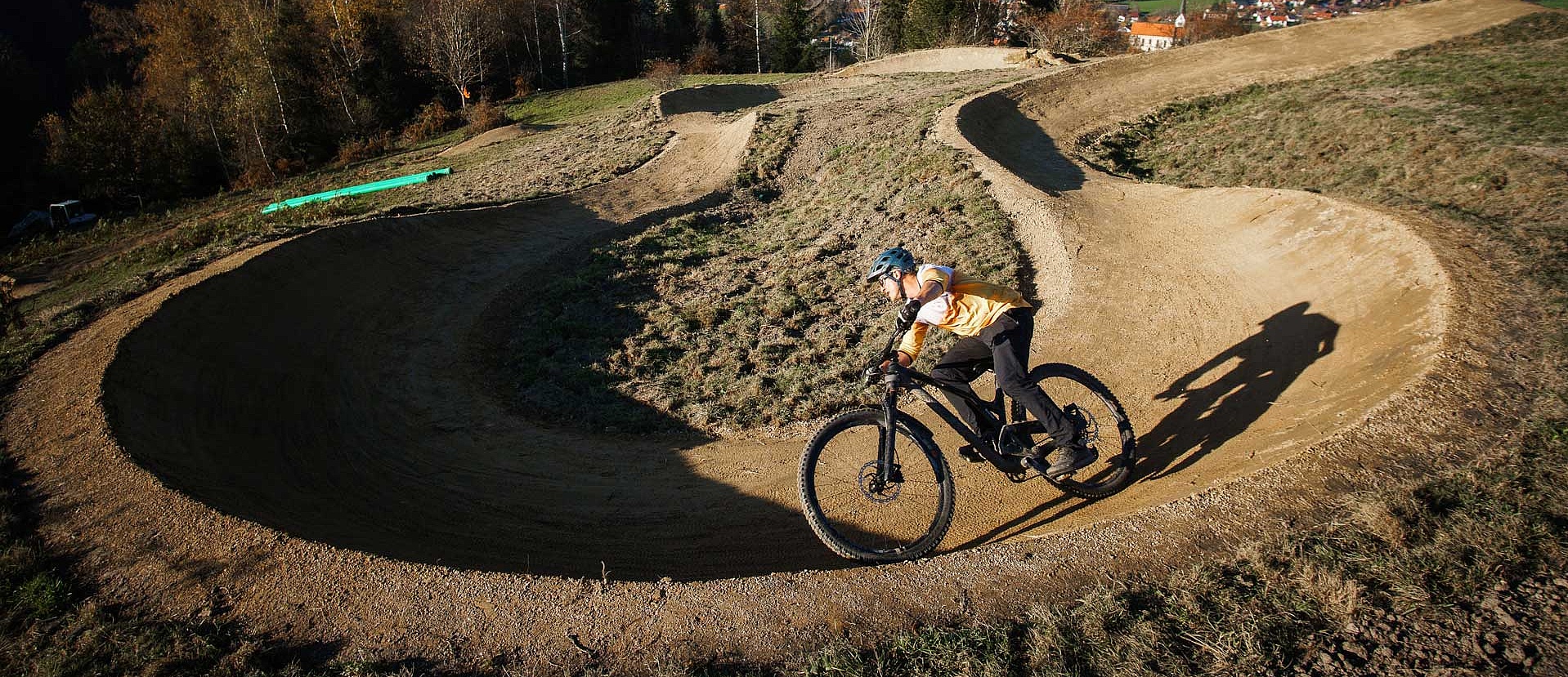 Mountainbiker in Steilkurve mit Ausblick auf Allgäuer Landschaft im Bikepark Weitnau