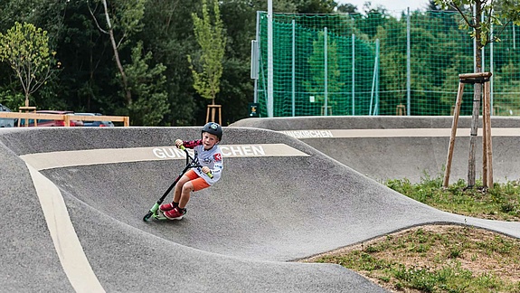 [Translate to Französisch:] Child with scooter rides in pump track