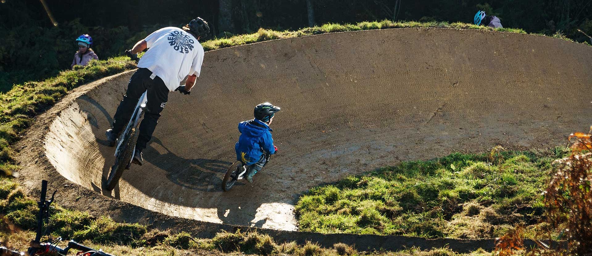 Father and child riding berm together at Bikepark Weitnau