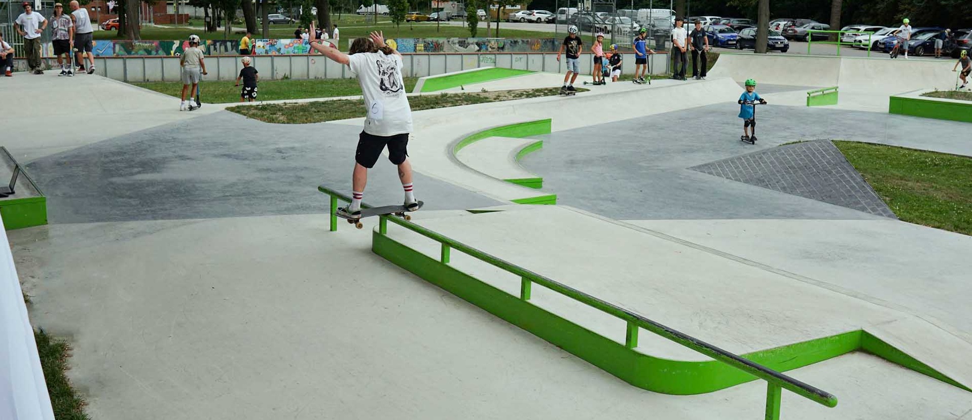 Skater balanciert auf einem grünen Rail im modernen Skatepark Stockerau mit Blick auf das Gelände.