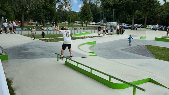 Skater balanciert auf einem grünen Rail im modernen Skatepark Stockerau mit Blick auf das Gelände.