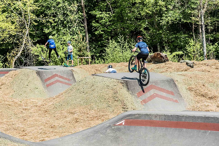 Kinder mit Rollern und Rädern auf Pumptrack