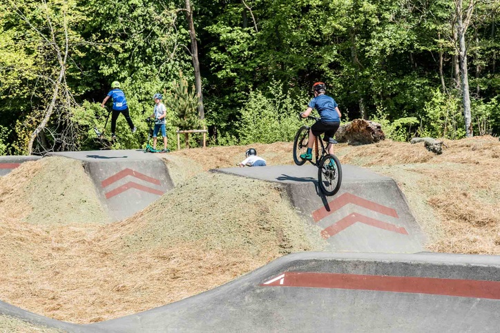 Children with scooters and bikes on the pump track
