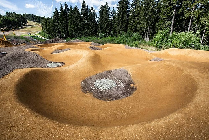 Ochre-coloured pump track at the edge of the forest