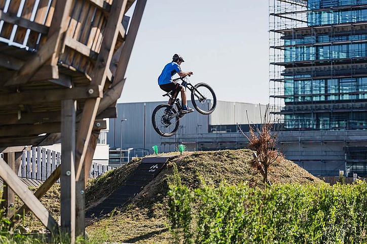 Biker jumps onto table in bike park in front of office building