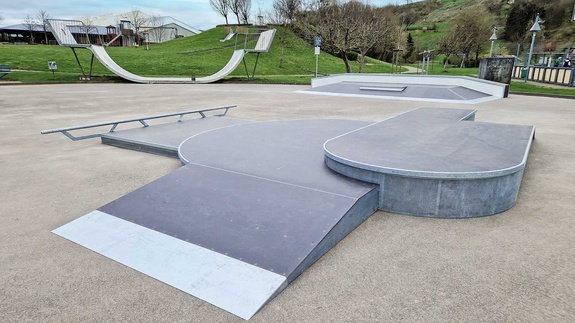 Outdoor view of the Lauchringen ramp park featuring various skate elements like rails, funboxes, and a halfpipe in the background.