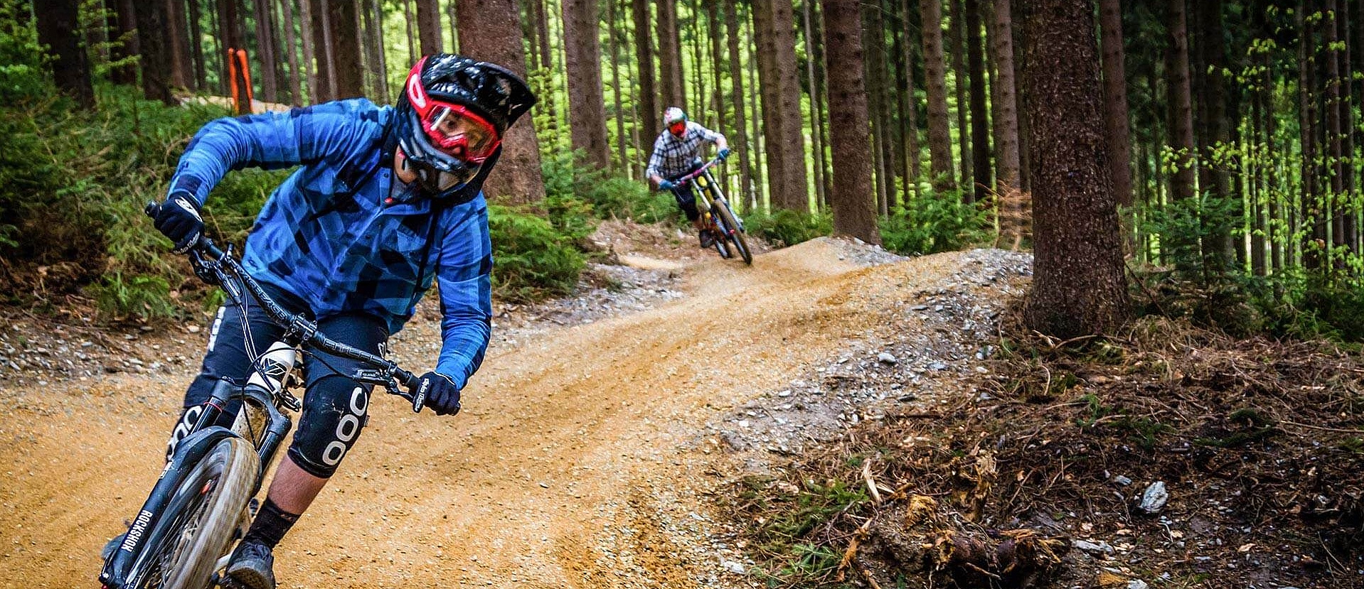 Two equipped bikers ride in the bike park in the forest