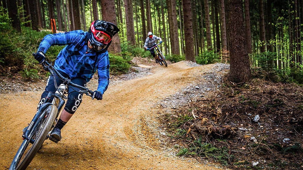 Two equipped bikers ride in the bike park in the forest