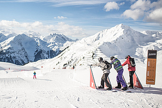 Drei Skifahrer stehen an Startgates und sind bereit los zu fahren