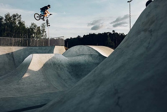 [Translate to Chinesisch:] Man with BMX jumps in BMX park