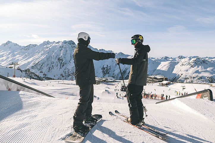 Eine Snowboarderin und ein Skifahrer geben sich die Faust im Snowpark Ischgl