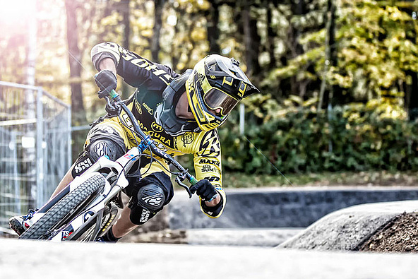 Man with fullface helmet riding in pump track in a curve