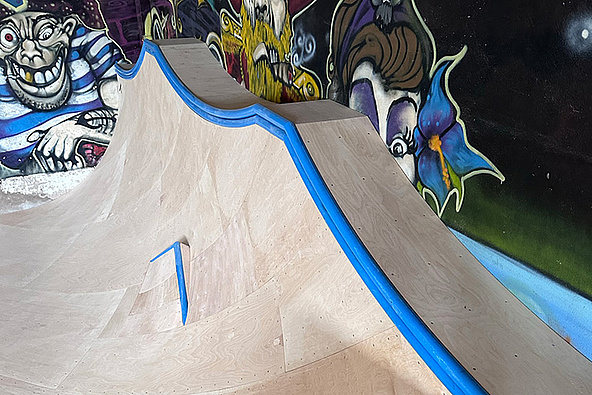 Quarterpipe mit blauen Copings in der Skatehalle Mühlhausen vor Graffiti-Wand