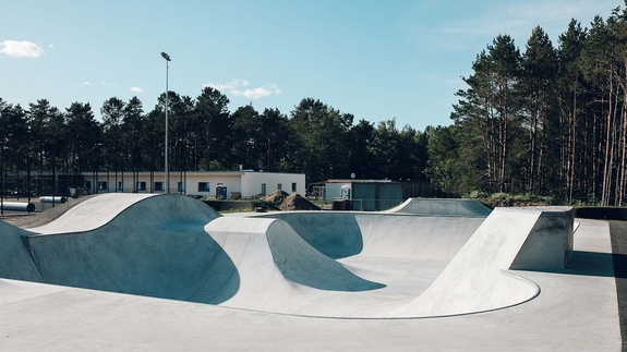 Wide angle shot of a professional action sports park featuring a combination of skate elements and pump track sections.