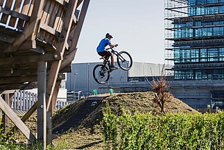 Biker springt auf Table im Bikepark vor Bürogebäude