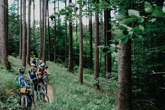 Children stand with their bicycles in a queue in the forest