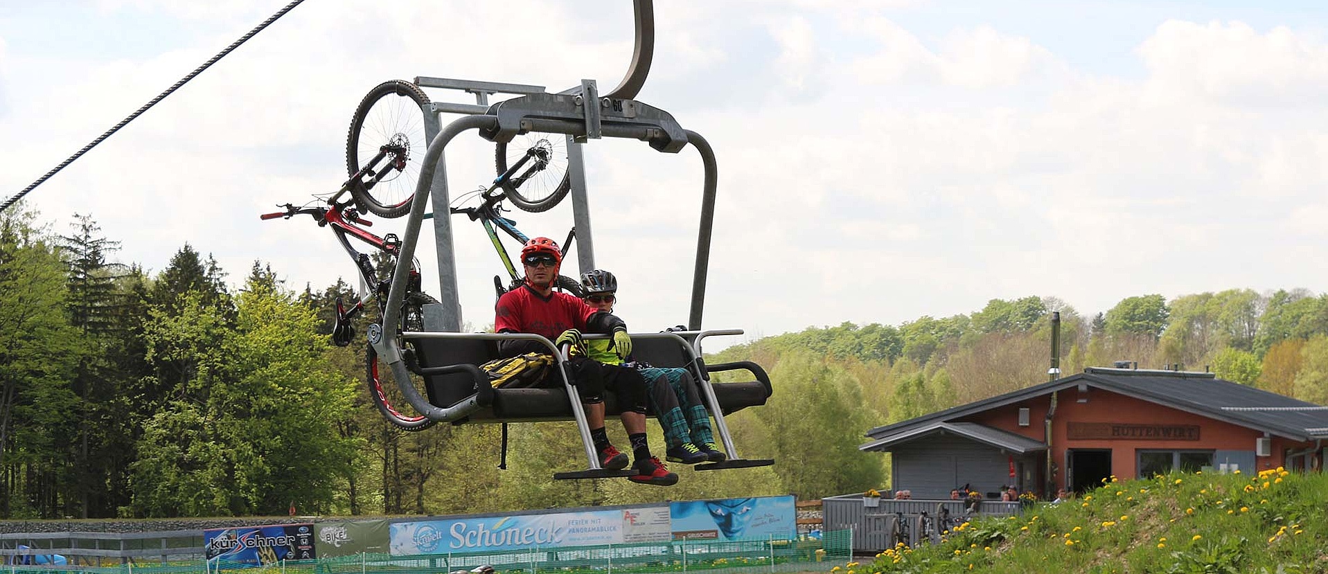 Two mountain bikers ride up chairlift