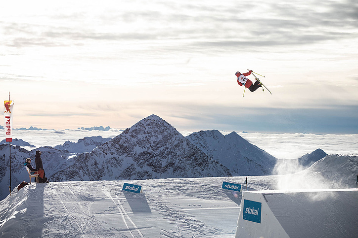 Skier after jump in the air in front of mountain panorama