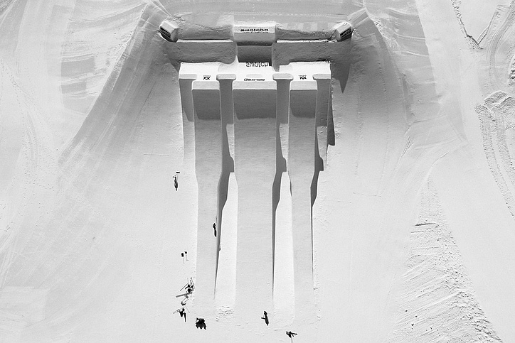 Schwarz-Weiß-Luftaufnahme des Swatch Snowparks Schilthorn mit großen Kickern und langen Schattenspuren.