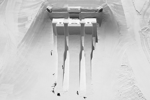 Schwarz-Weiß-Luftaufnahme des Swatch Snowparks Schilthorn mit großen Kickern und langen Schattenspuren.