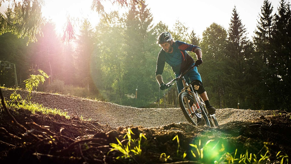 Mountain biker in a curve on a flow trail at the edge of the forest