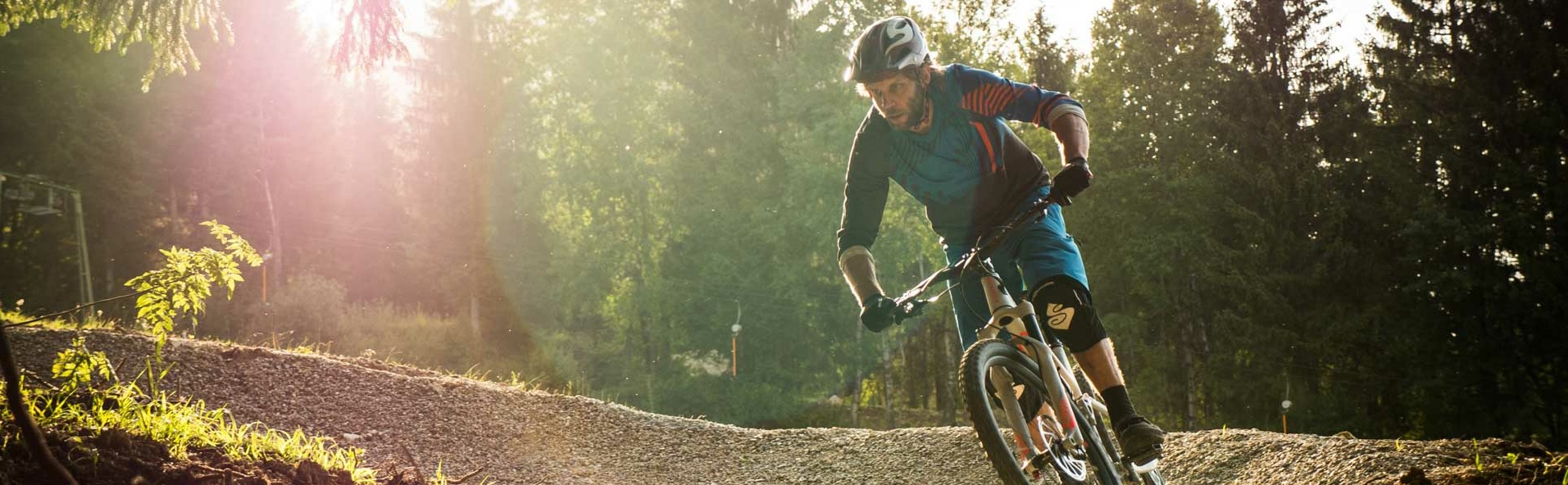 Mountain biker in a curve on a flow trail at the edge of the forest