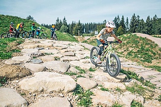 Young girl riding downhill on mountain bike over uneven stones
