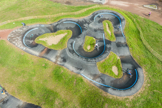 Vue plongeante à la verticale d'un pumptrack en boucle à Cublize avec plusieurs usagers sur la piste.