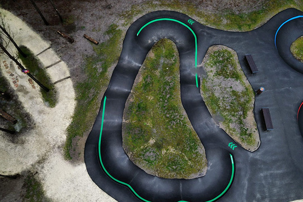 Vue aérienne du Pumptrack Audenge avec des pistes en asphalte sinueuses dans la forêt