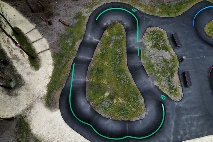 Luftaufnahme des Pumptrack Audenge mit geschwungenen Asphaltbahnen im Waldgebiet