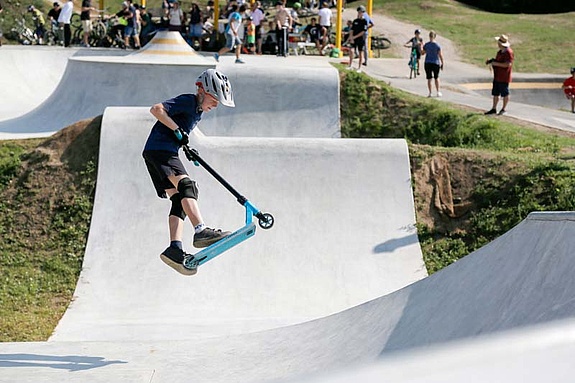 Junge springt mit seinem Scooter im Scooterpark