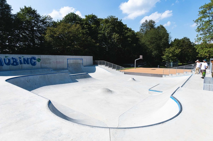 View of empty in-situ concrete skate park with basketball court in the background
