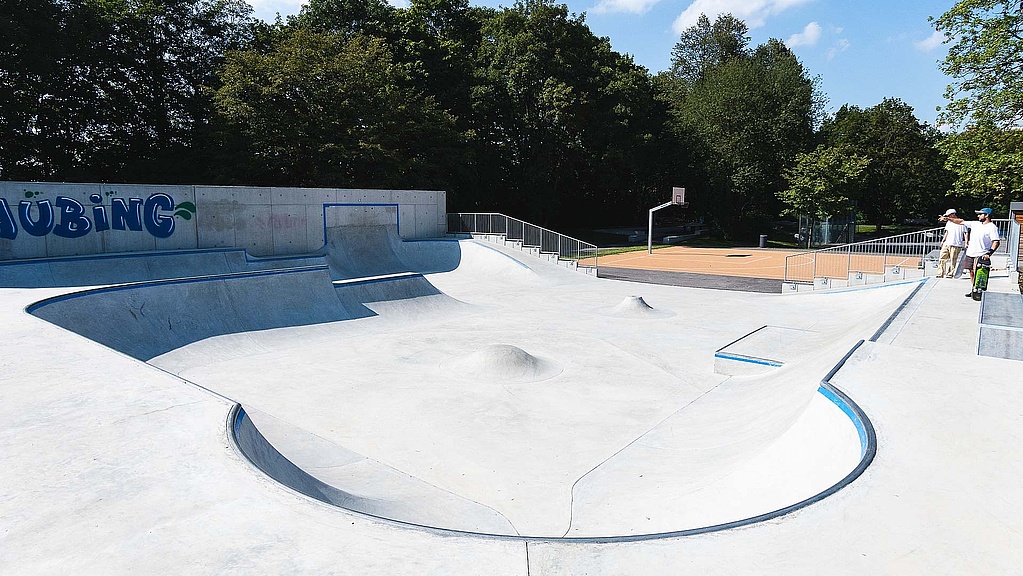 View of empty in-situ concrete skate park with basketball court in the background