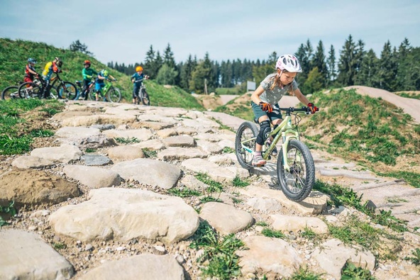 Young girl riding downhill on mountain bike over uneven stones