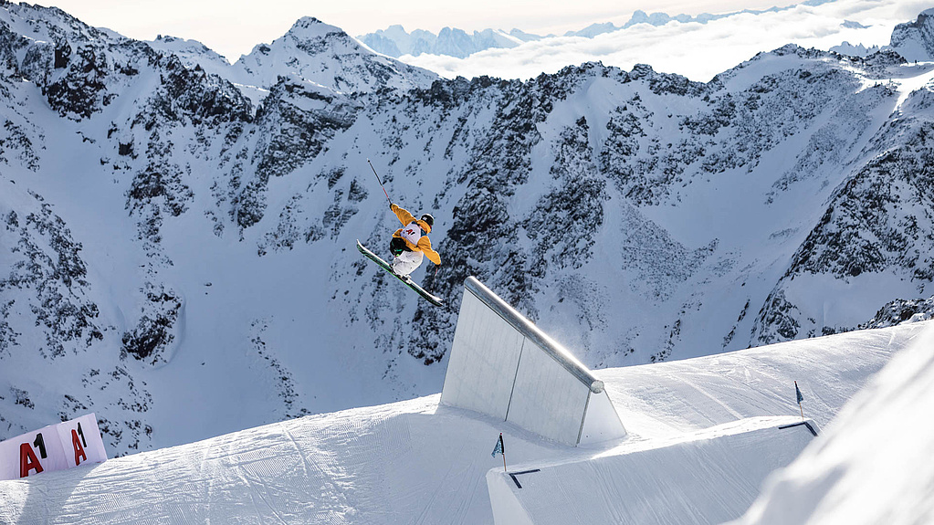 Skier is after jump in the air in front of mountain panorama