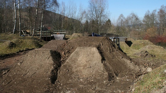 Dirt park with blue sky and forest in background