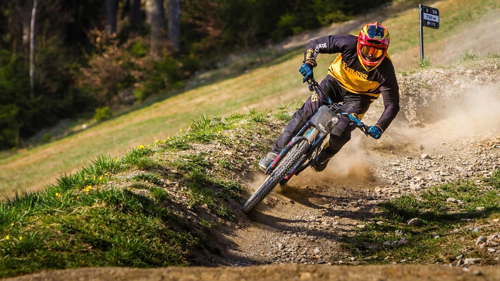 Biker in Vollmontur auf einer Kurve im Downhilltrail