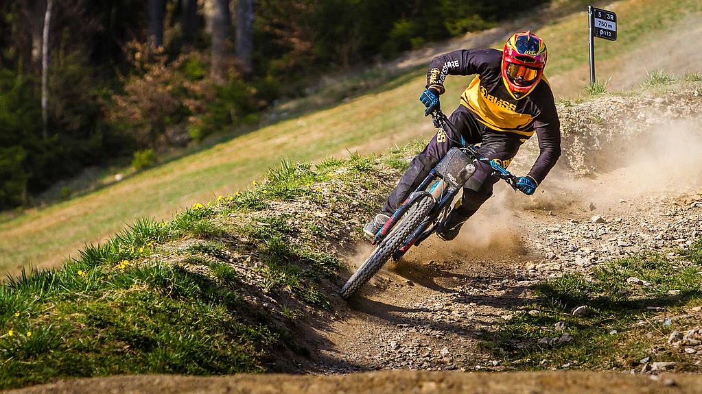 Biker in full gear on a curve in downhill trail