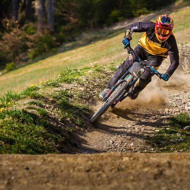 Biker in Vollmontur auf einer Kurve im Downhilltrail
