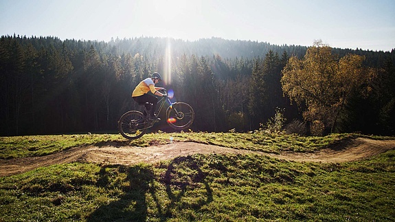 Mountain biker jumping over pump track feature at Bikepark Weitnau