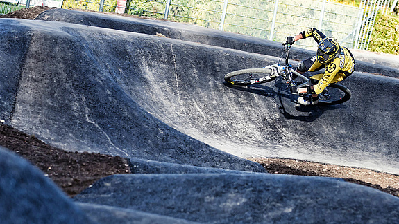 Man with whole safety equipment rides a curve in the pump track